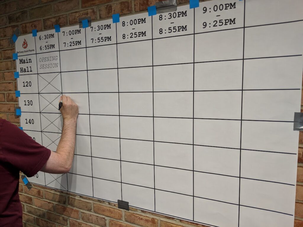 An empty schedule grid, with someone beginning to write on it.